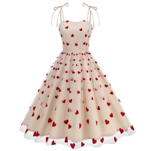 Detailed close-up of beige mesh dress featuring red heart patterns and tie-straps