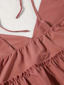 Detail eines staubrosa V-Ausschnitt Tops mit schmalen Trägern und plissierter Stoffstruktur