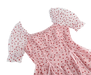 Dettaglio dell'abito in tulle rosa con cuori rossi e nastri intrecciati sullo stile corpetto