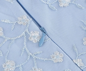Détails de broderie florale blanche et fermeture éclair invisible sur robe bleu clair