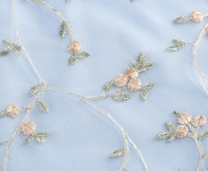 Close-up of golden floral embroidery and leaf patterns on light blue tulle fabric