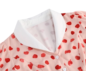 Detailed view of pink dress with heart print, white lapel collar and heart buttons