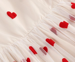 Detail of red flocked heart embroidery on double-layered mesh tulle fabric dress