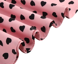 Detail of pink vintage dress fabric with black heart print and neat stitching