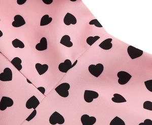 Close-up of pink fabric with black heart print and stitching detail of this elegant dress