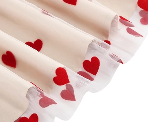Detail of cream fabric with red velvet hearts and delicate white tulle embroidery