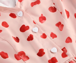 Close-up of pink chiffon dress with red heart prints and white heart-shaped buttons