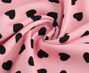 Detail of pink chiffon fabric with black heart print and soft pleated texture