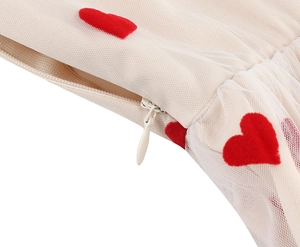 Detail of hidden zipper on beige mesh dress featuring embroidered red heart patterns