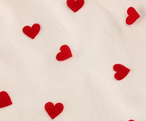 Detailed close-up of white mesh fabric featuring red flocked heart-shaped embroidery patterns