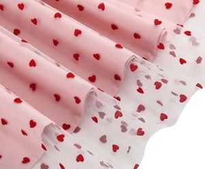 Dettaglio del vestito rosa a strati con rete bianca e motivi a cuore rosso