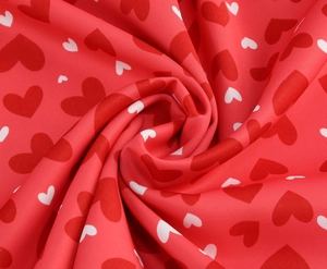 Détail du tissu à imprimé cœur rouge et blanc montrant une texture lisse et drapée