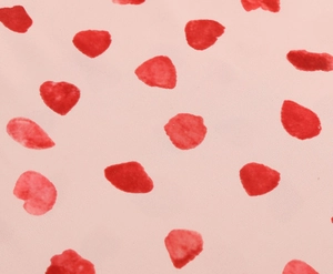 Close-up of soft pink fabric featuring artistic red watercolor polka dot print textures