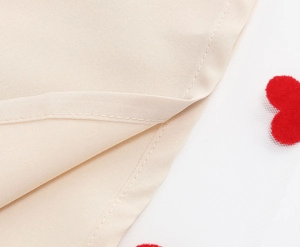 Detail of apricot fabric and white mesh with red flocked heart embroidery