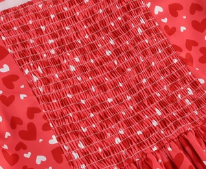 Détail du corsage froncé sur une robe rouge à imprimé cœurs et plis élastiques