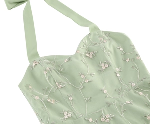 Detail of sage green sleeveless dress with halter neck bow and floral mesh embroidery