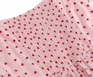Dettaglio del tessuto a rete rosa con cuori rossi floccati e texture a punto smock