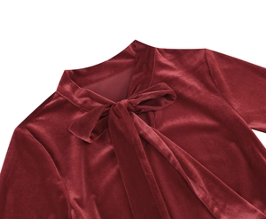 Detail of burgundy velvet dress neckline featuring an elegant bow tie and rich texture