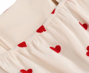 Close-up of red flocked heart patterns on delicate mesh dress with pleated elastic waist
