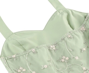 Detail of light green mesh dress featuring delicate floral embroidery and vine patterns