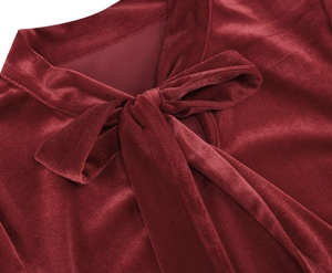 Close-up of the elegant bow-tie neckline on a vintage-style burgundy velvet dress