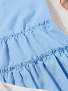 Detailaufnahme von hellblauem Stoff mit gestuften Rüschen und hochwertiger Plissee-Struktur