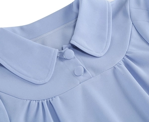 Close-up of light blue dress collar with fabric buttons and pleated neckline details