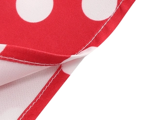 Detailed close-up of double-needle stitching and white polka dots on red cotton fabric
