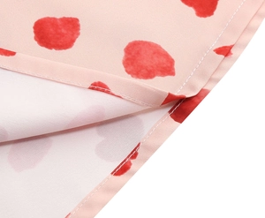Detailed macro shot of the pink dress fabric with red polka dot print and double-stitched hem