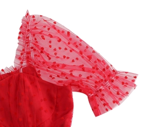 Dettaglio del vestito in rete rossa con motivo a cuori e maniche a sbuffo chic