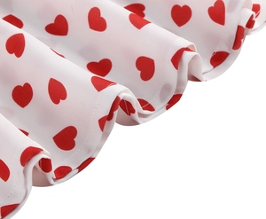 Detail view of white fabric with red heart print and fine stitching on the dress hem
