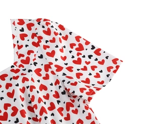 Détail de la manche à volants sur robe blanche avec motifs de petits cœurs rouges et noirs