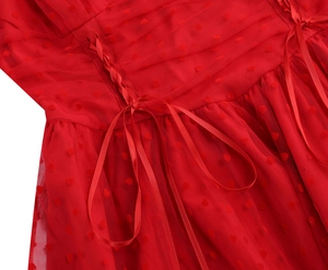 Dettaglio di abito rosso con motivi a cuore in mesh e allacciatura laterale in raso