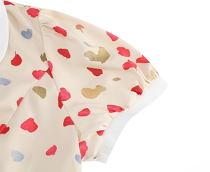 Detail of short puff sleeve featuring multi-color heart prints on cream fabric texture