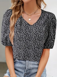 Detail of V-neck floral blouse with puffed sleeves and delicate white patterns on black