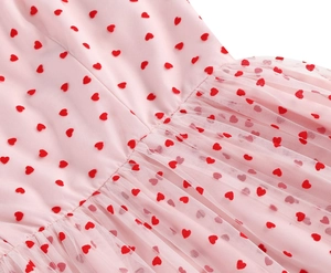 Detailed macro view of pink mesh fabric with red heart embroidery and pleated waistline