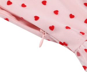 Close-up detail of pink mesh fabric with red heart embroidery and invisible zipper closure