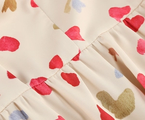 Close-up of lightweight beige woven fabric with heart petal prints and pleated texture details