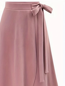 Détail d'une jupe portefeuille à taille haute avec nœud latéral et tissu drapé doux