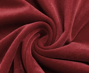 Macro shot of elegant wine red velvet fabric with flowing spiral pleats and silky texture
