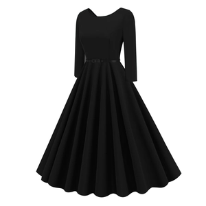 Detail of a vintage black A-line dress featuring a slim leather belt and pleated wide hem