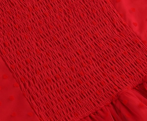 Dettaglio del tessuto rosso con trama a punto smock e materiale chiffon a pois