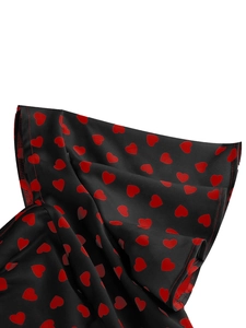 Detail of elegant black dress fabric featuring red heart prints and fine stitched edges
