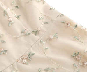 Detail of elegant champagne mesh dress with floral embroidery and vine patterns
