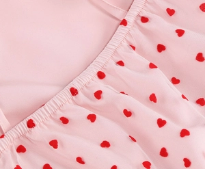 Detail of pink tulle dress featuring red flocked heart patterns and elasticated gathering