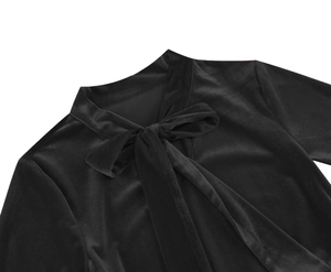 Detail of elegant black velvet neckline featuring a bow tie and stand collar design