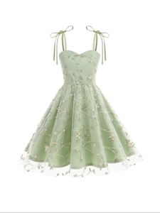 Détail d'une robe en tulle vert menthe avec broderie florale et bretelles à nœuds