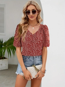 Detailed close-up of a red floral V-neck top with puff sleeves and gold chain bag