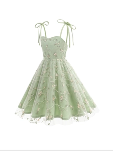 Détail de la robe en tulle vert clair avec broderie florale et bretelles à nœuds