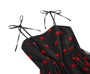 Detail of black mesh dress featuring red heart embroidery and delicate bow shoulder straps